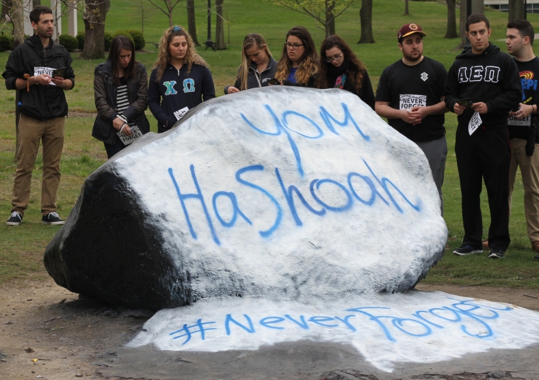 Nikos Frazier | Kent Stater  "Yom HaShoah," or Holocaust Remeberance day, and "#NeverForget" are freshly painted on the Rock as members of Alpha Epsilon Pi Fraternity and Hillel at Kent State stand and recite scriptures on Wednesday, May 4th, 2016.